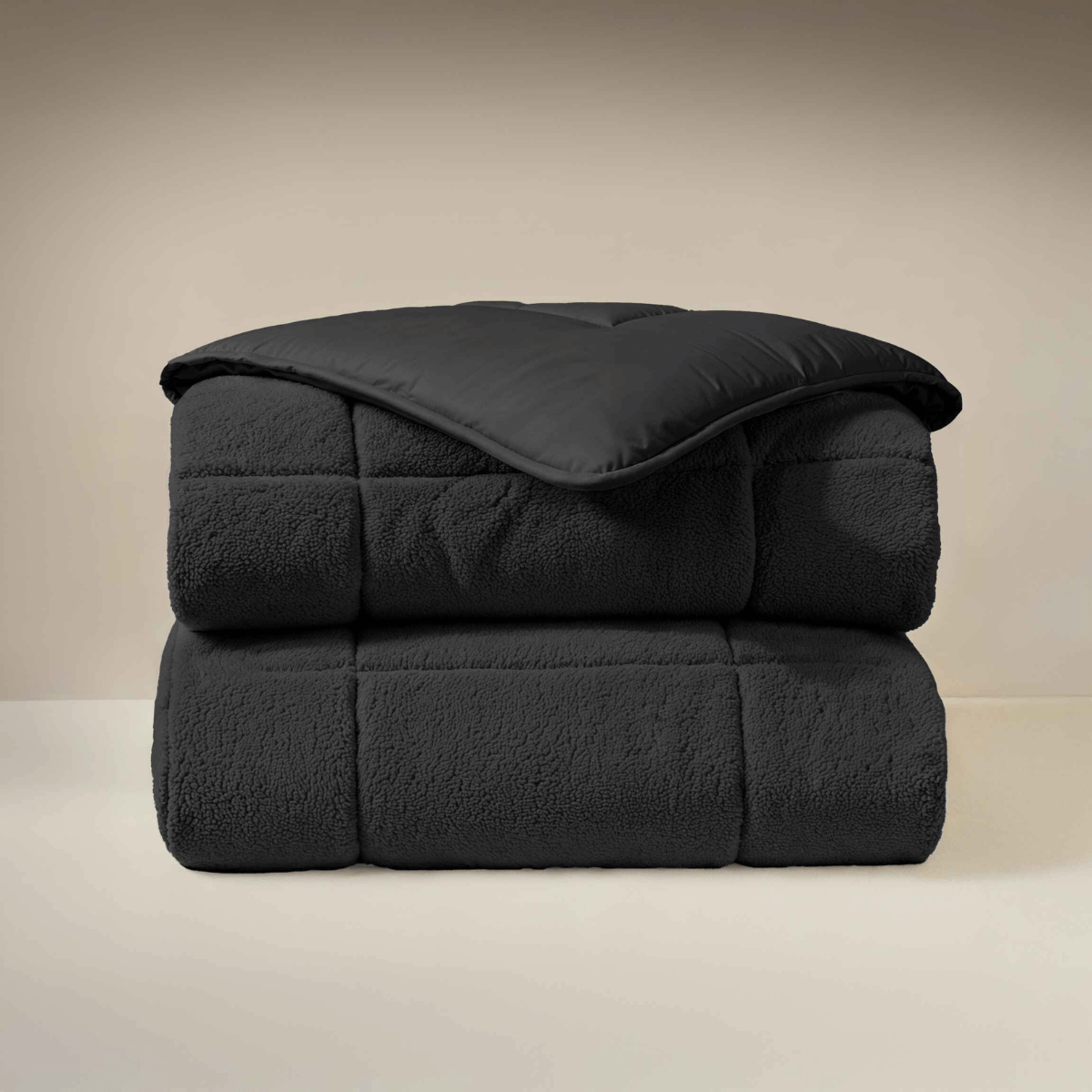 Une couette pliée Zelesta Teddybed - Anthracite, à la texture douce et matelassée et au design de couette pelucheux, est empilée sur un fond neutre.