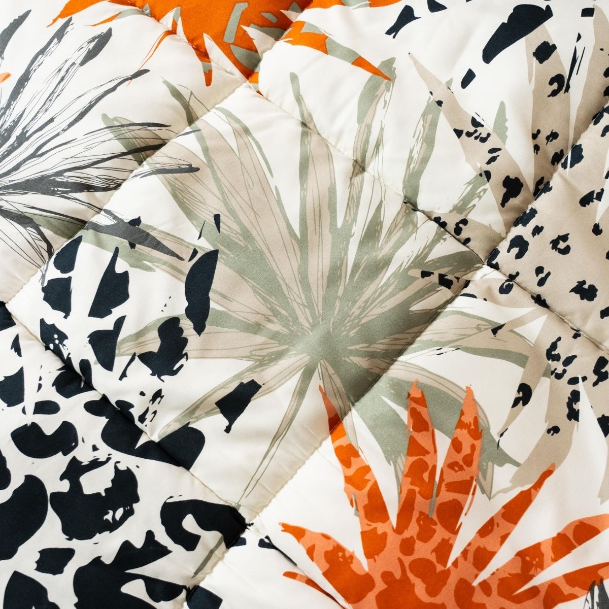 Gros plan sur le tissu thermorégulateur hypoallergénique en microfibre matelassé du lit Zelesta Wonderbed Light - Jungle Orange, qui présente un imprimé botanique et animalier abstrait dans les tons orange, noir, gris et beige. Élégant pour toute chambre à coucher.