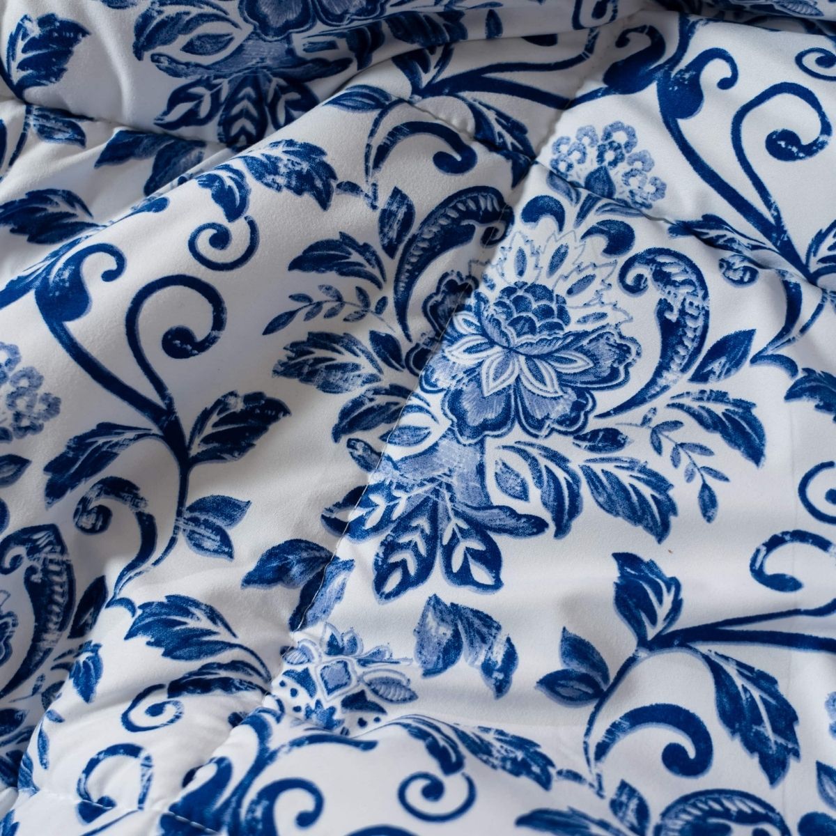 Gros plan sur le lit magique Zelesta Wonderbed Light - Motif Néerlandais, qui présente un motif floral et feuillu bleu matelassé sur fond blanc.