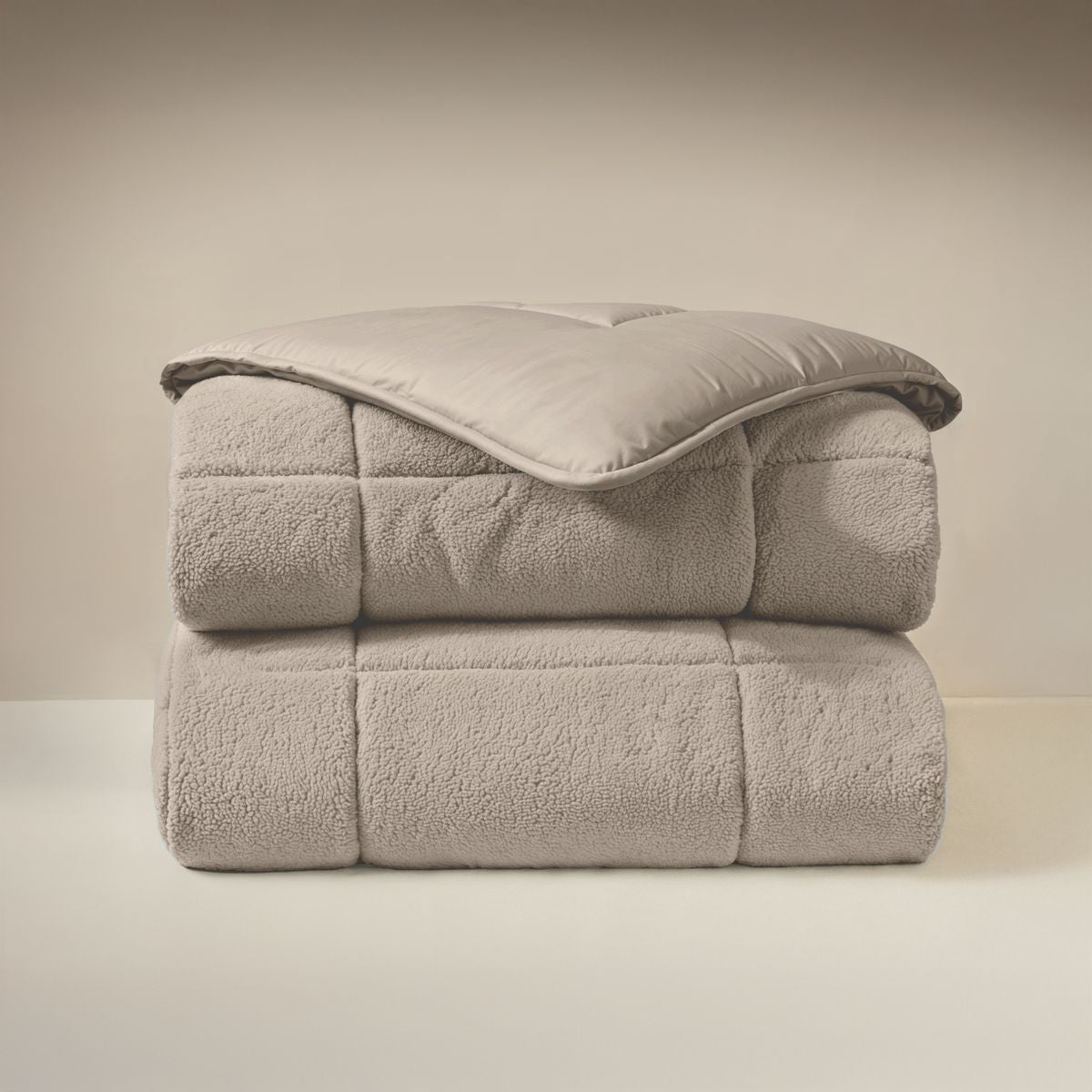 Le Teddybed de Zelesta - Taupe, un édredon doux et moelleux au motif de nounours, est soigneusement plié sur une surface claire, sur un fond neutre.