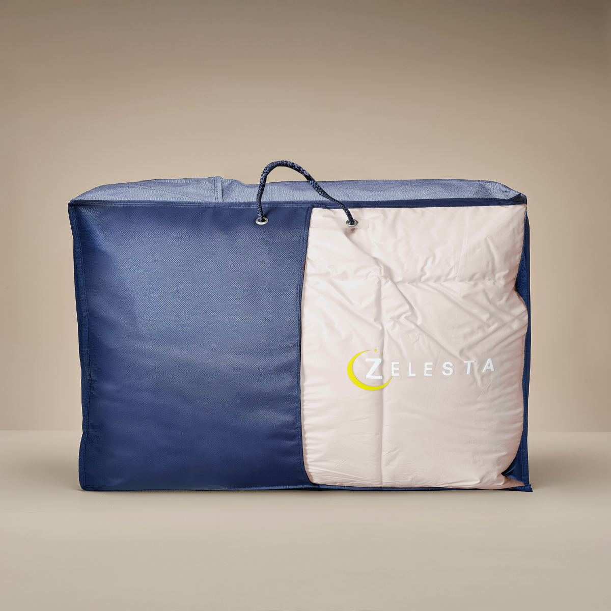 Un grand sac de rangement bleu à fermeture éclair, partiellement ouvert pour révéler une couette blanche pliée, étiquetée Zelesta Premiumbed Light Coton - Soie & Crème de Noix de Coco.