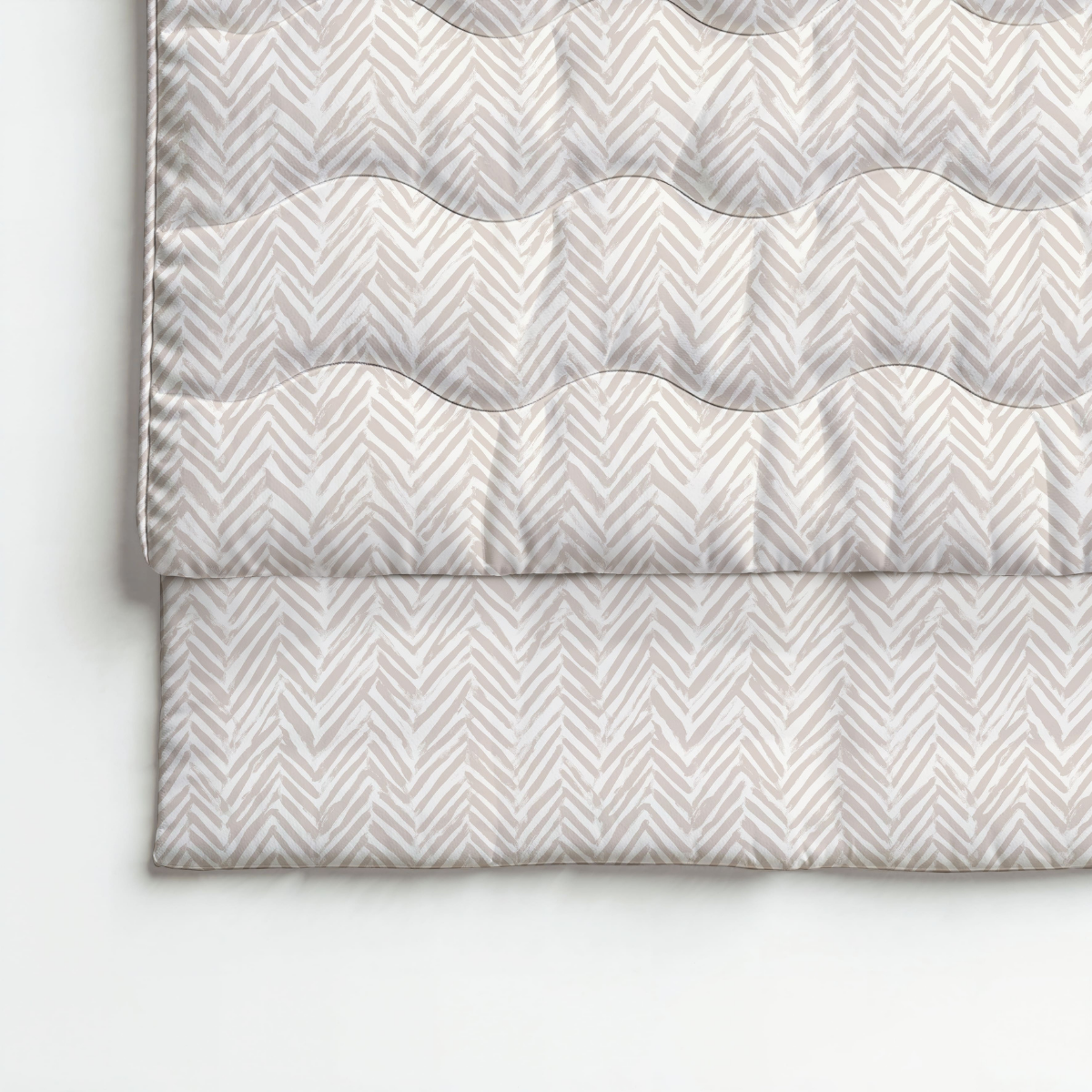 Couette pliée beige et blanche avec un motif à chevrons, présentée sur une surface plane - cette Zelesta Royalbed Coton - Crème Naturelle ajoute de l'élégance et du confort à toute chambre à coucher.