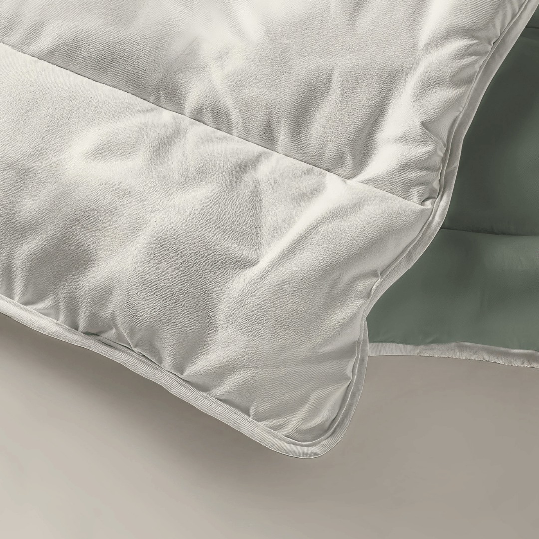 Gros plan sur le Zelesta Royalbed Light - Vert Pastel & Crème couette, plié pour révéler son extérieur blanc et son intérieur vert pastel, présenté sur une surface neutre.