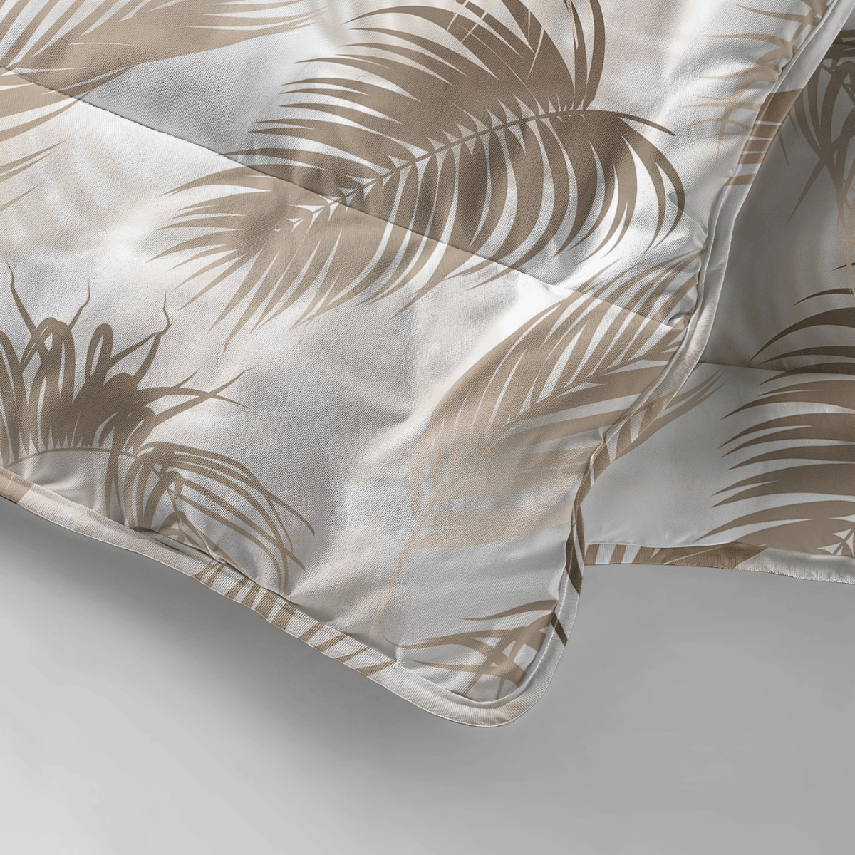Gros plan sur la couverture Zelesta Royalbed - Feuilles de Palmier, de couleur claire avec un motif de feuilles de palmier beige, drapée et légèrement pliée sur une surface blanche - un confort élégant avec un design de couverture intégré.
