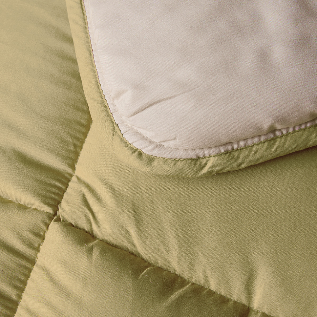 Gros plan sur le tissu matelassé vert clair avec un écusson beige, présent dans le Petit lit Zelesta - Crème & Olive, qui comprend une housse intégrée pour plus de commodité.