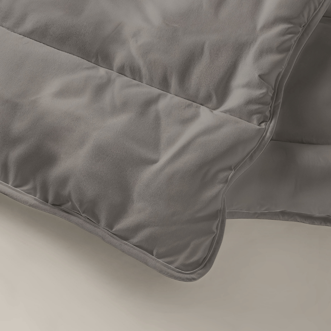 Gros plan sur le Zelesta Royalbed Light - Gris Tendre, une couette matelassée grise lavable en machine, aux coutures apparentes et à la texture douce et lisse.