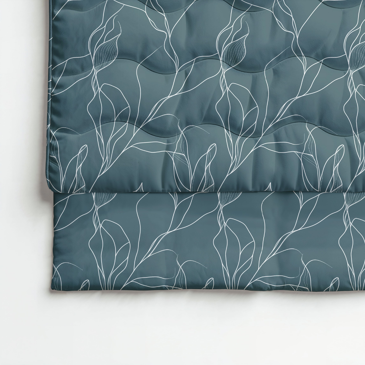 Le Zelesta Royalbed Coton - Feuilles Blanches, une couette sarcelle foncée pliée avec housse intégrée avec un motif botanique linéaire blanc, est présenté sur une surface blanche.