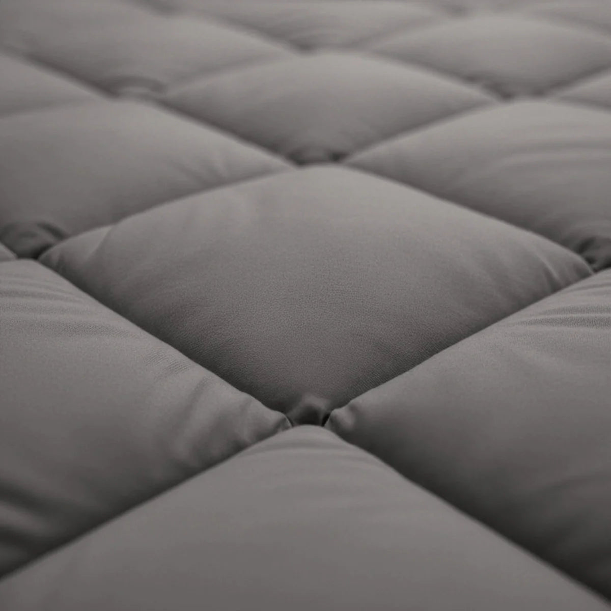 Gros plan sur un tissu matelassé gris avec des coutures en forme de losange, présent sur le Zelesta Royalbed Diamant - Gris-Marron couette toutes saisons.
