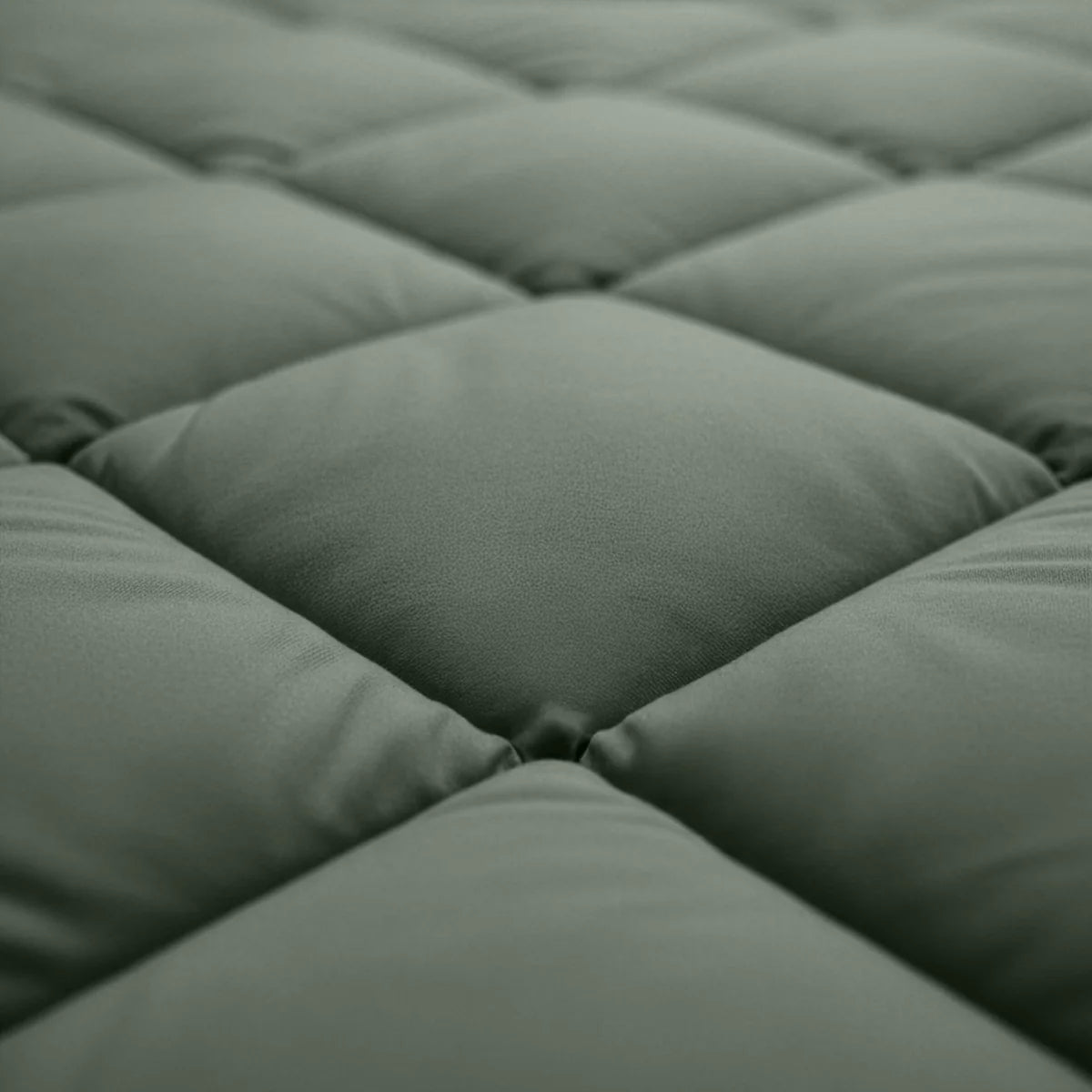 Gros plan sur le tissu matelassé vert Zelesta Royalbed Diamant - Vert, mettant en évidence son quadrillage de carrés en relief et matelassés.