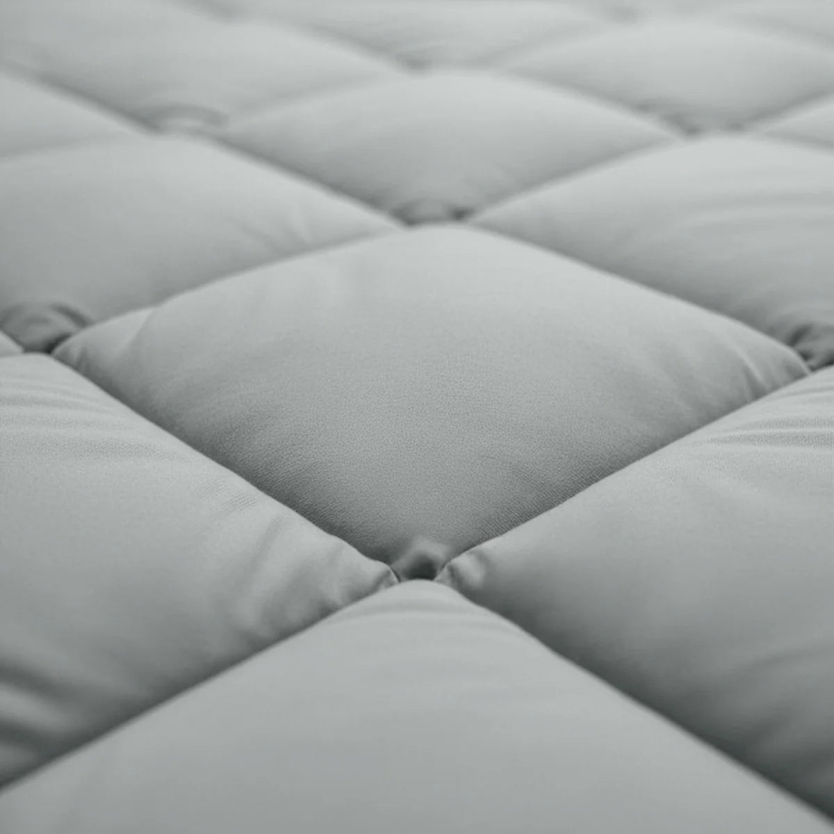 Gros plan sur la surface matelassée et rembourrée du Zelesta Royalbed Diamant - Gris-Bleu, dont les carrés sont régulièrement espacés et la texture douce et moelleuse - parfaite pour une expérience de couette thermorégulatrice.