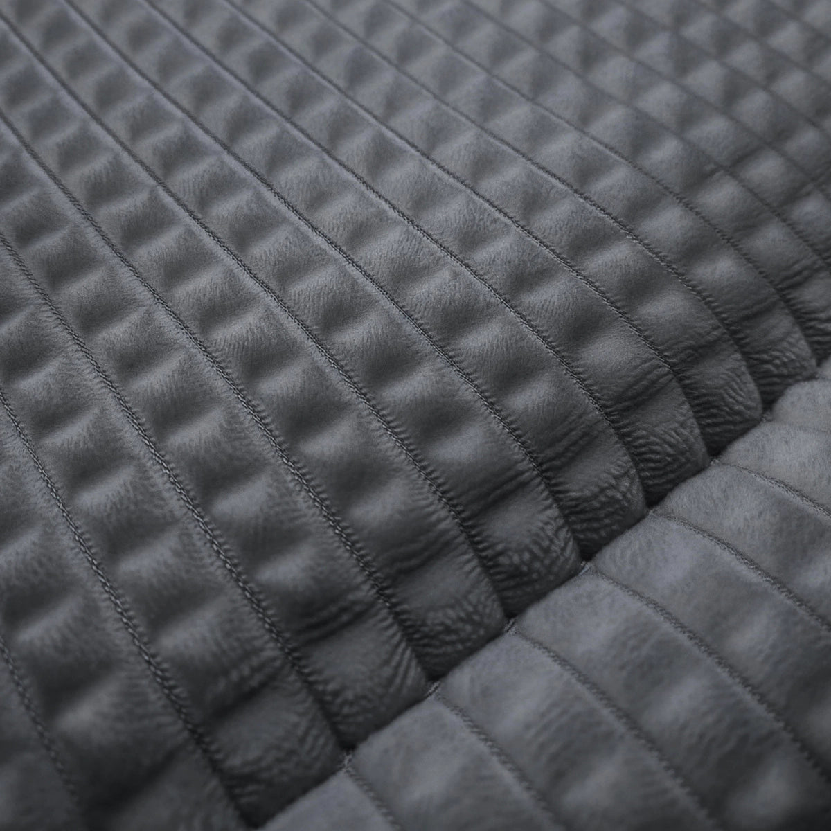 Gros plan sur la couette Zelesta Teddy Check - Anthracite, qui présente une surface grise texturée et matelassée avec un motif en grille et des sections rembourrées en relief - idéale pour une couette à carreaux élégante et douillette.