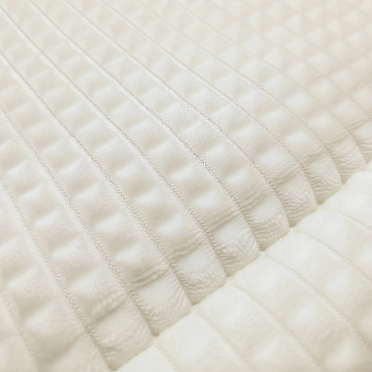 Gros plan sur Zelesta Teddy Check - Crème, un tissu matelassé blanc avec des lignes et des carrés en relief, évoquant l'aspect douillet d'une couette à carreaux.