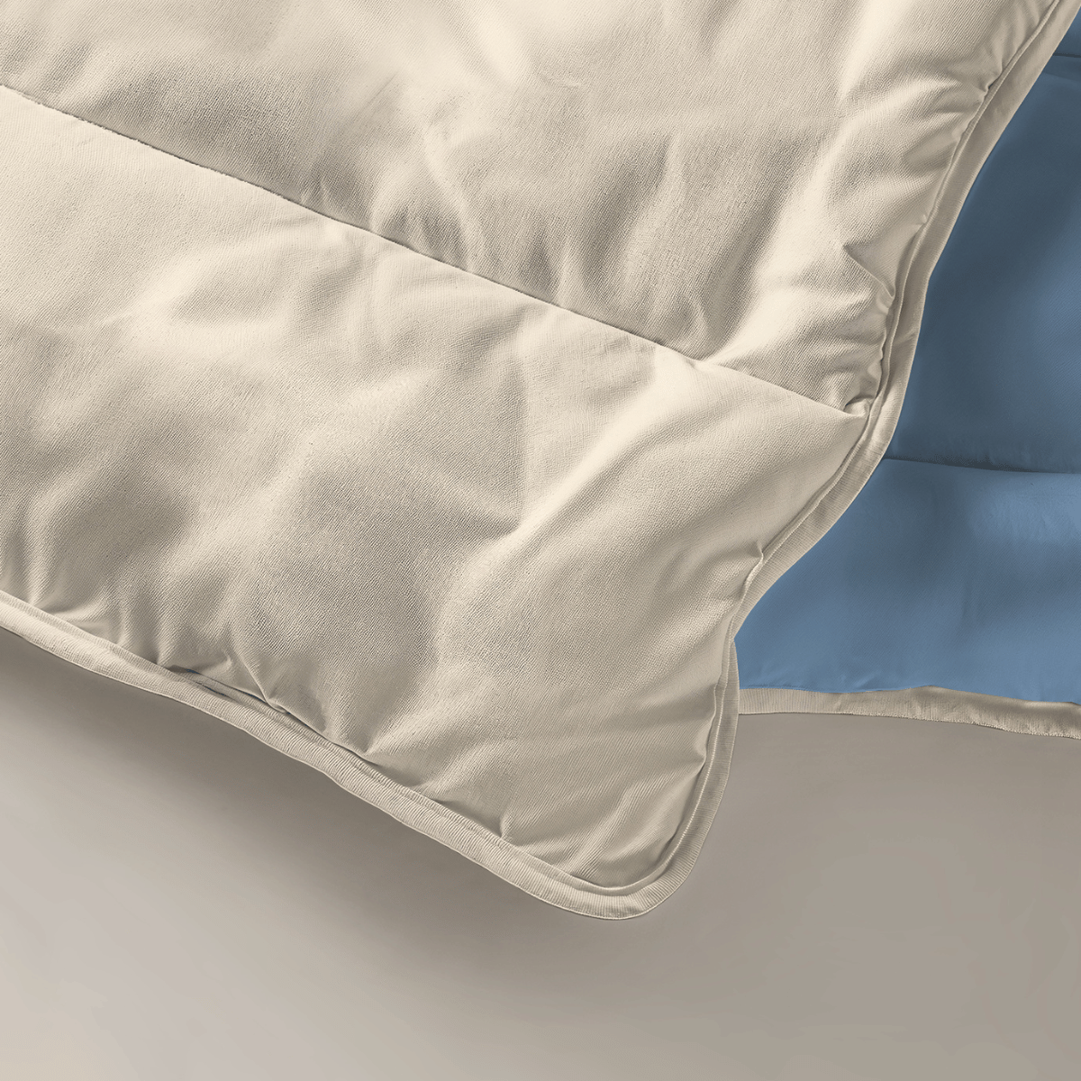Un gros plan de la couette Zelesta Royalbed Light - Brume Bleue & Plage de Sable couette été montre des surpiqûres, un tissu beige et une doublure bleu clair. Cette couette lavable en machine allie confort et commodité.