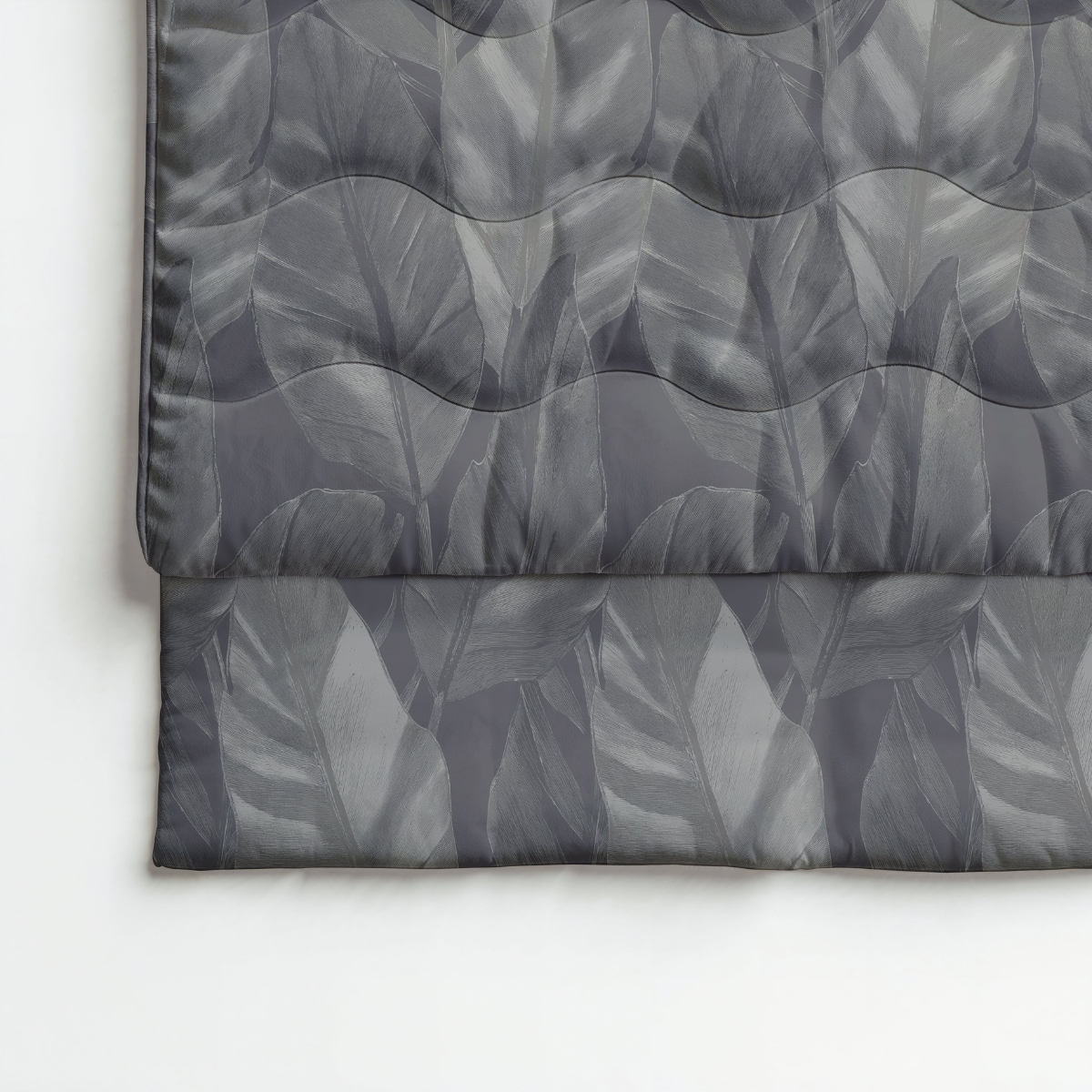 Gros plan sur le tissu matelassé Zelesta Royalbed Coton - Cygne Noir thermorégulatrice, présentant un motif de feuilles grises et soigneusement plié sur une surface blanche.