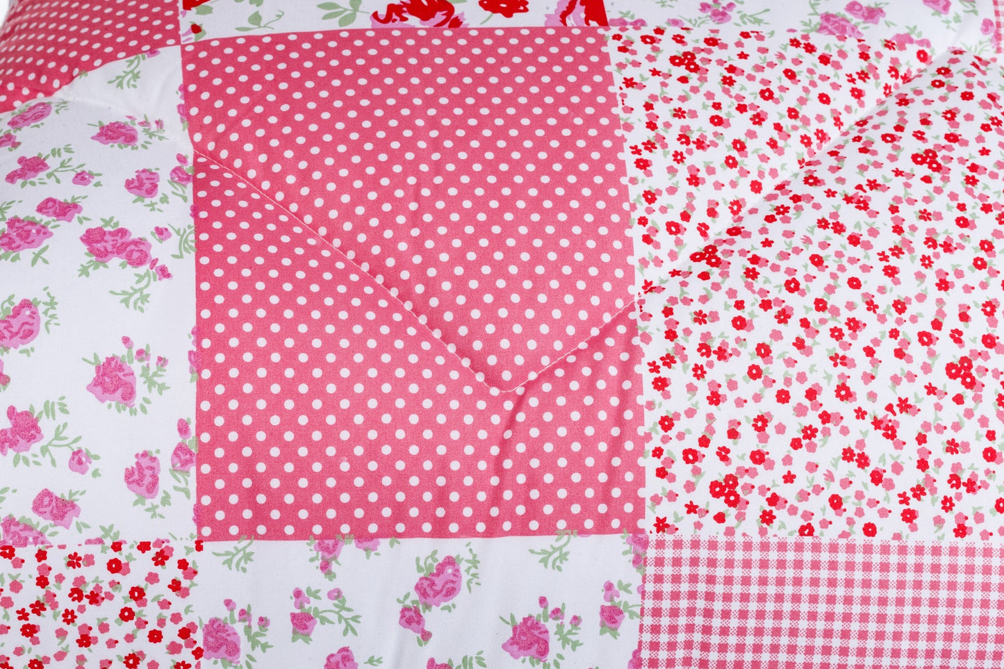 Gros plan sur le lit magique Zelesta Wonderbed Light - Patchwork Rose, une douillette couette été avec un patchwork rose, blanc et rouge aux motifs floraux, à pois et à carreaux, réalisée en microfibre thermorégulatrice pour un confort tout en légèreté.