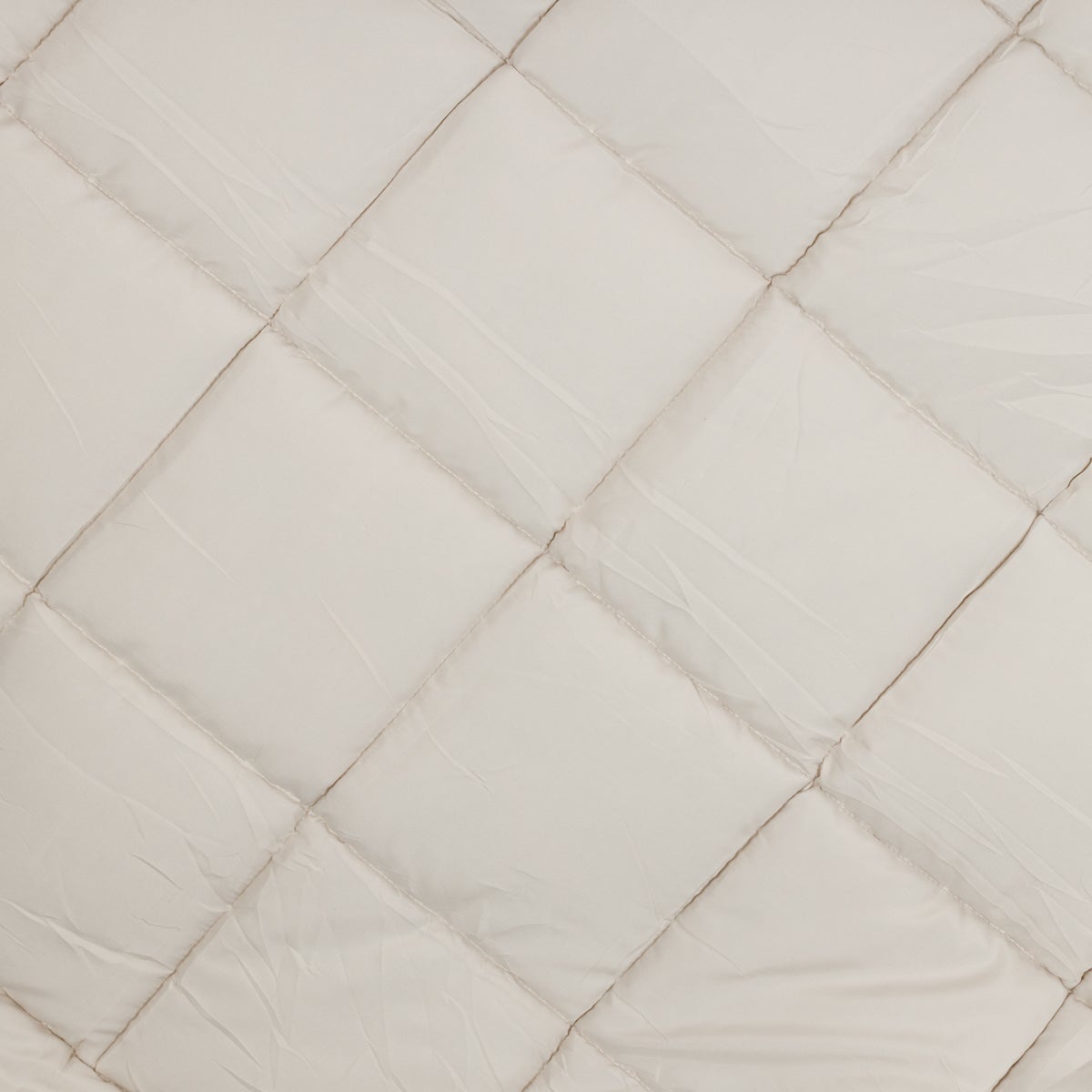 Gros plan sur le lit Zelesta Easy - Bleu & Mastic, doté d'une microfibre blanche matelassée avec un motif en losange et des coutures apparentes qui mettent en valeur sa texture douce.