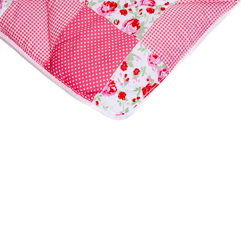 Le lit magique Zelesta - Patchwork Rose est un édredon rose et blanc à pois, à carreaux et à motifs floraux, offrant un confort similaire à celui d'une couette en microfibre, sur fond blanc.