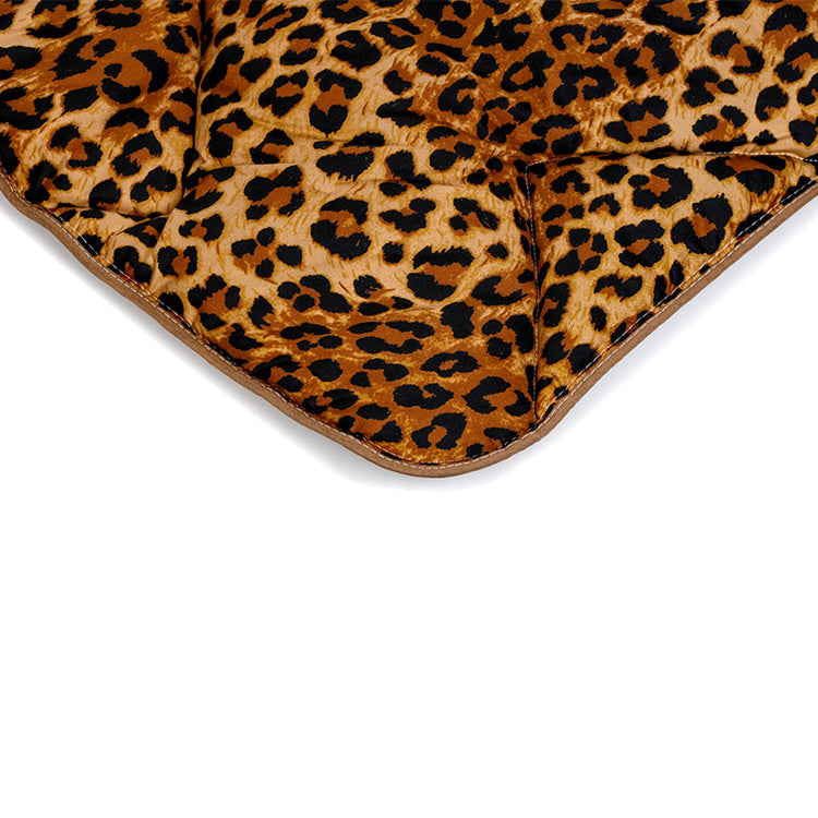 Gros plan d'un tissu rembourré à l'imprimé léopard marron, noir et beige, avec des sections cousues et un bord incurvé-Zelesta Wonderbed - Peau de Jaguar anti-allergène couette lavable.